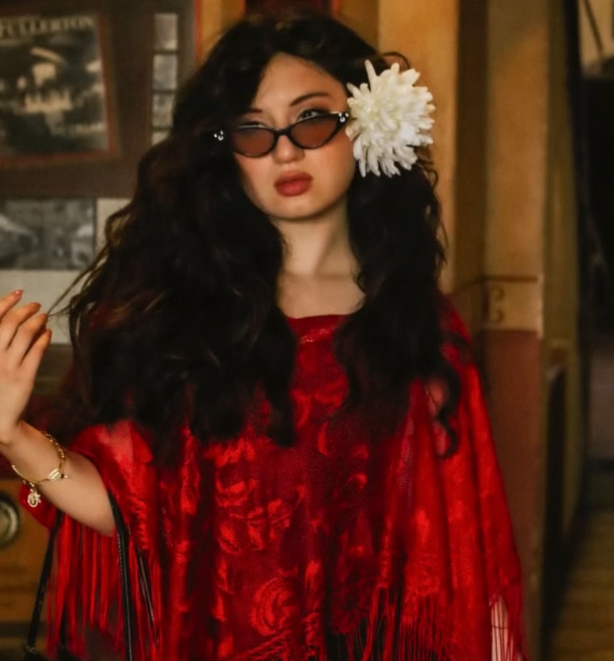 AALBA in a red fringed shawl with a white flower in her hair